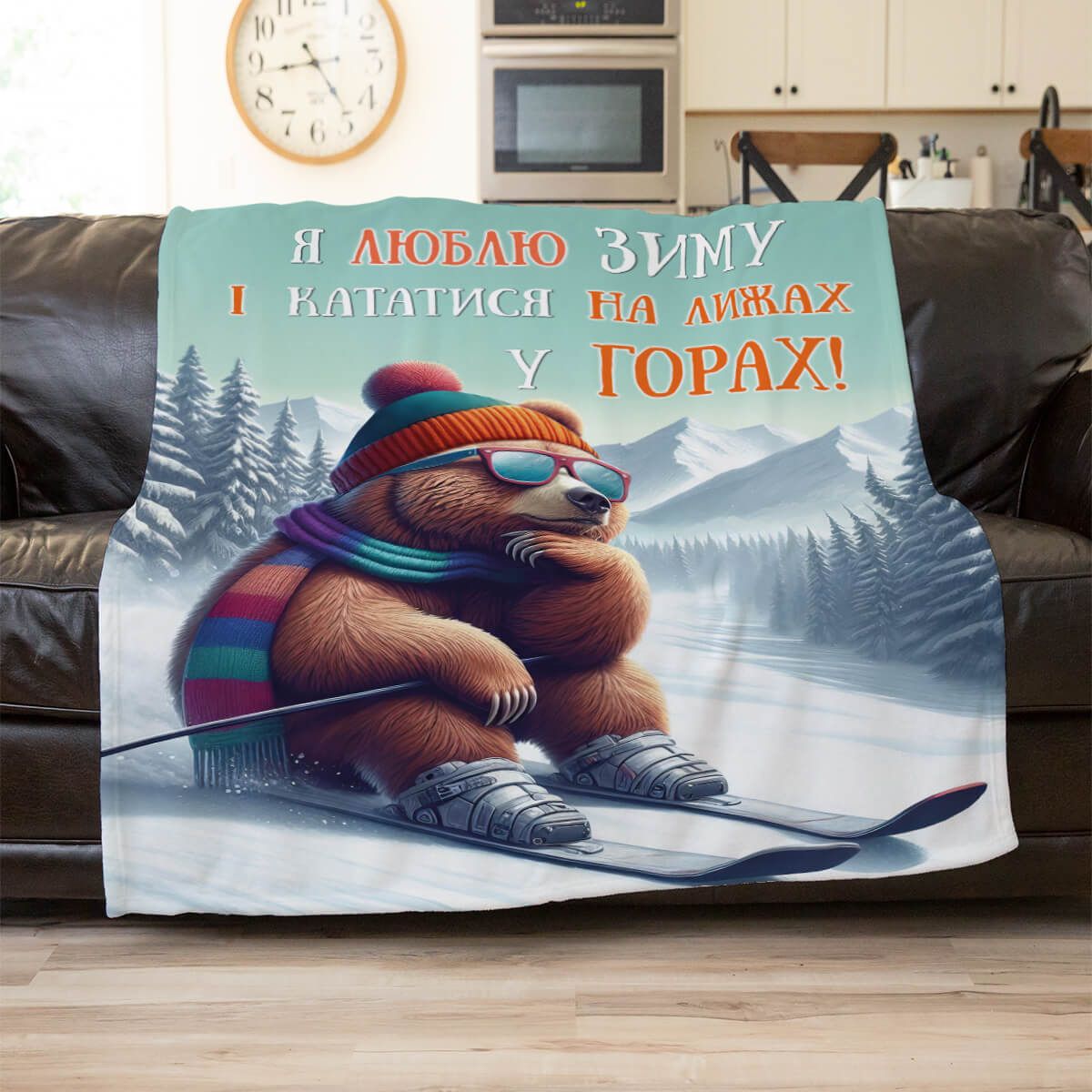 Плед із бурим ведмедем у шапці з помпоном, окулярах і шарфі на лижах серед засніжених гір, плед в інтер’єрі